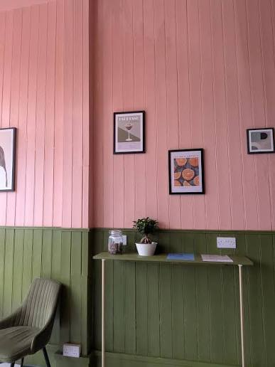 Peach and olive panelled wall with framed prints